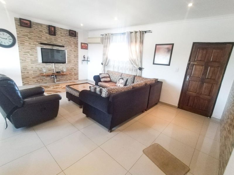 A living room featuring a stone accent wall, tiled flooring, and a split-system air conditioner, providing a functional and comfortable living space.