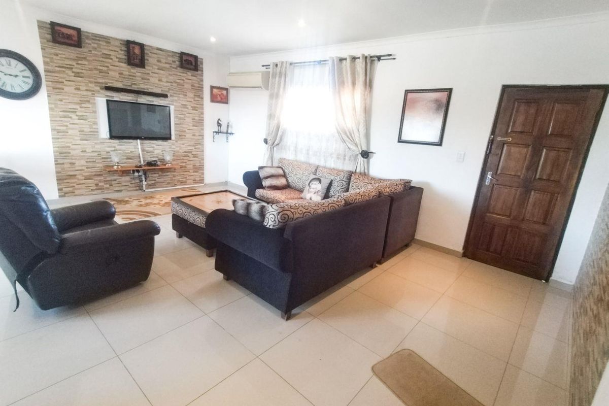 A living room featuring a stone accent wall, tiled flooring, and a split-system air conditioner, providing a functional and comfortable living space.