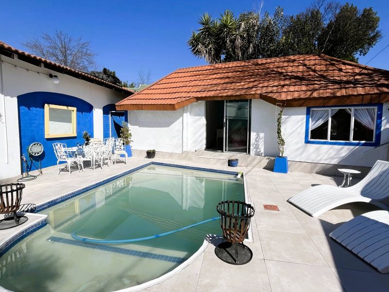 Outdoor pool area featuring a tiled patio, terracotta roof tiles, and direct access to the cottage via a sliding glass door.