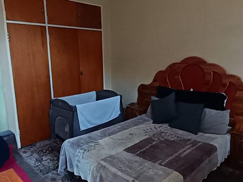 A bedroom featuring built-in wooden cupboards and a security gate leading to the exterior.