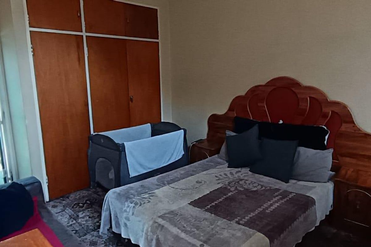 A bedroom featuring built-in wooden cupboards and a security gate leading to the exterior.