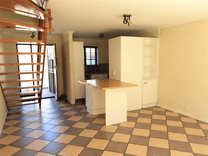 Open plan living area featuring a spiral staircase, tiled flooring, and a functional kitchen island with built-in cabinetry.