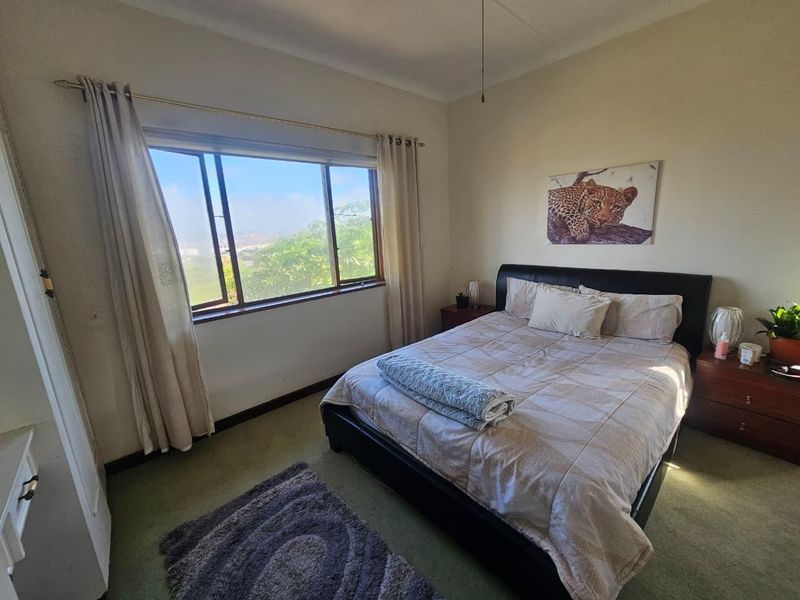 A standard bedroom featuring a large window with natural light and a ceiling fan, offering a comfortable space for rest.