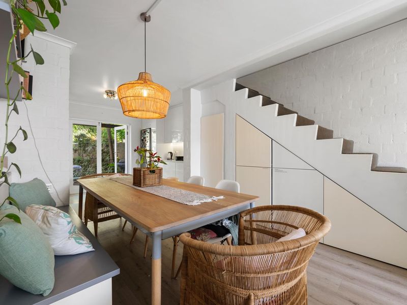 Open plan dining area featuring built-in under-stair storage, modern laminate flooring, and direct access to the rear garden through glass sliding doors.