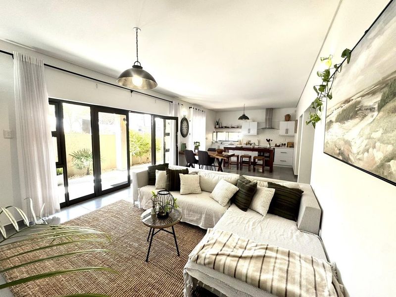 Spacious open-plan living and kitchen area featuring modern cabinetry, a central island, and large sliding doors providing seamless access to the outdoor patio.