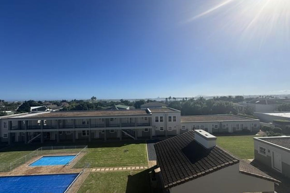An elevated aerial view of the apartment complex grounds, featuring communal swimming pools, landscaped lawns, and surrounding residential neighborhood.