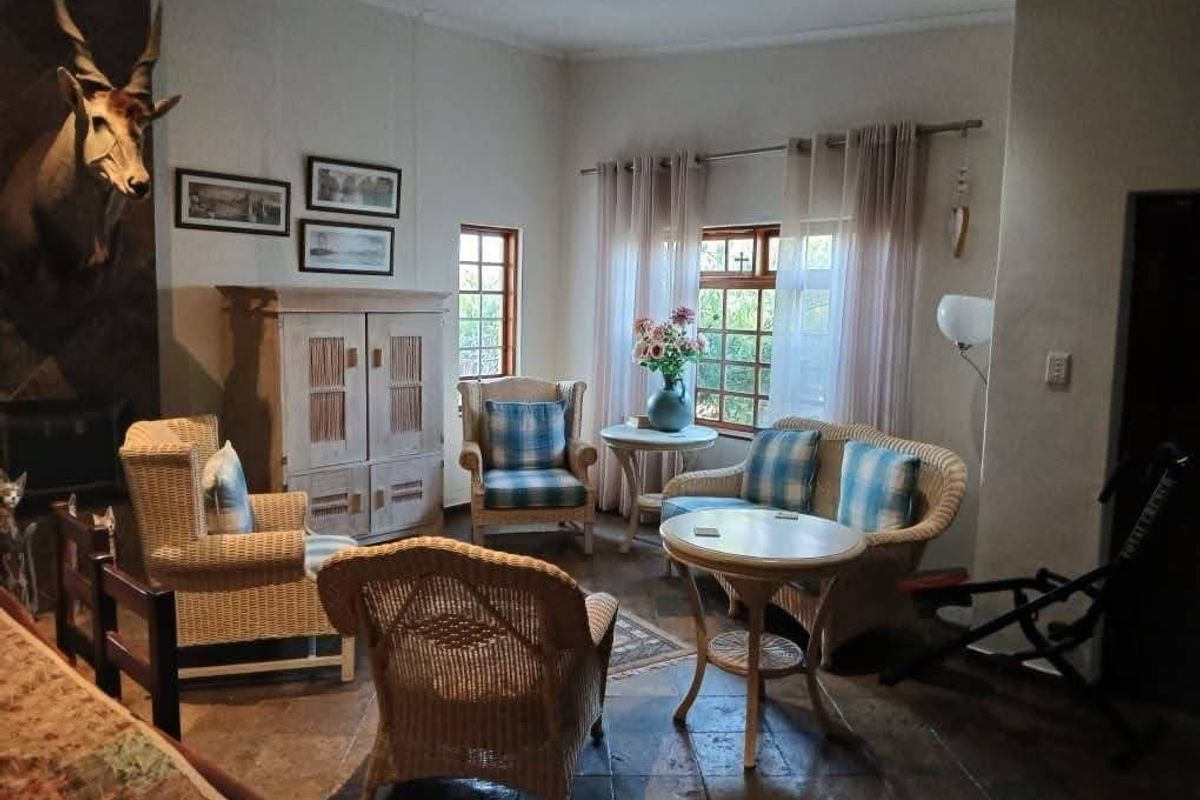 A cozy living room featuring stone tile flooring, a fireplace, and natural light through timber-framed windows.