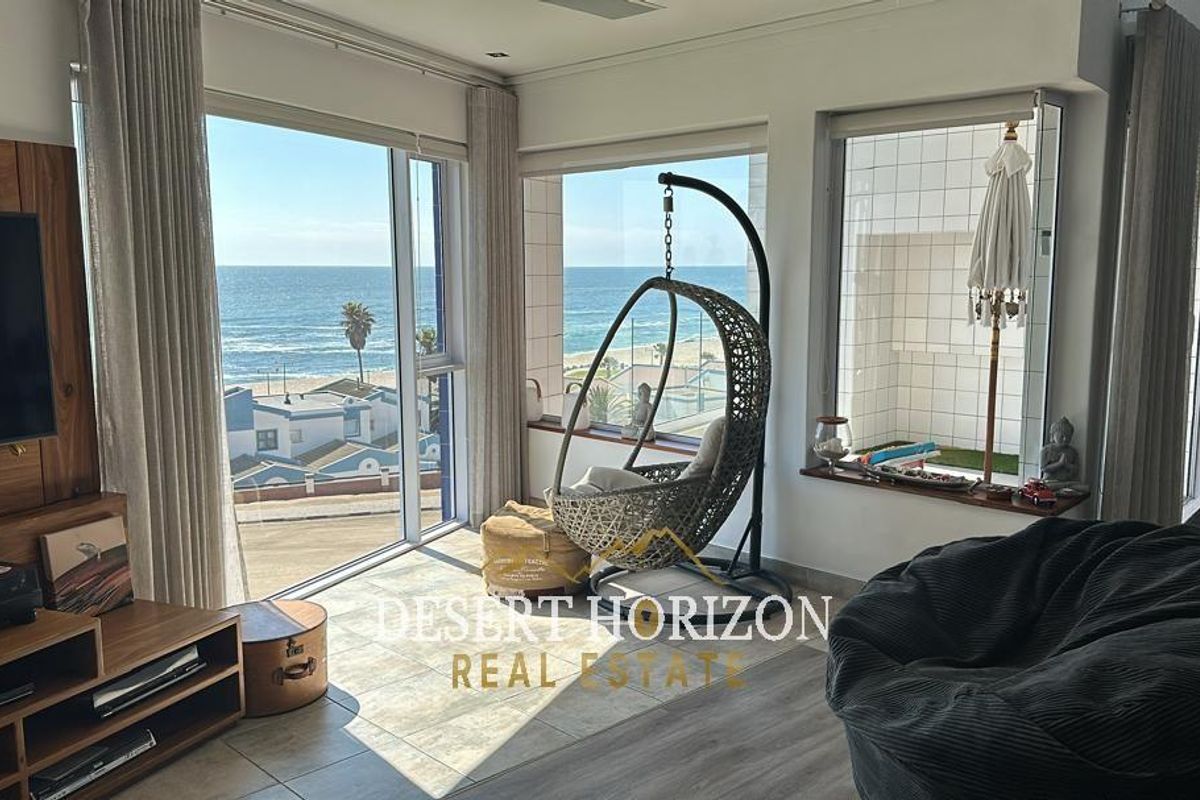 Spacious living area featuring large floor-to-ceiling windows with expansive ocean views and direct access to a private balcony.