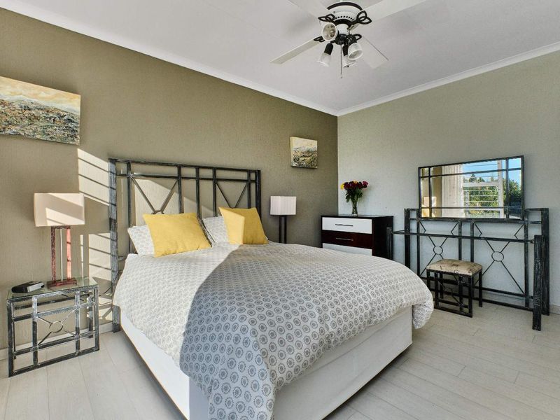 A well-lit bedroom featuring neutral wall tones, tiled flooring, and a functional ceiling fan, providing a comfortable and inviting living space.