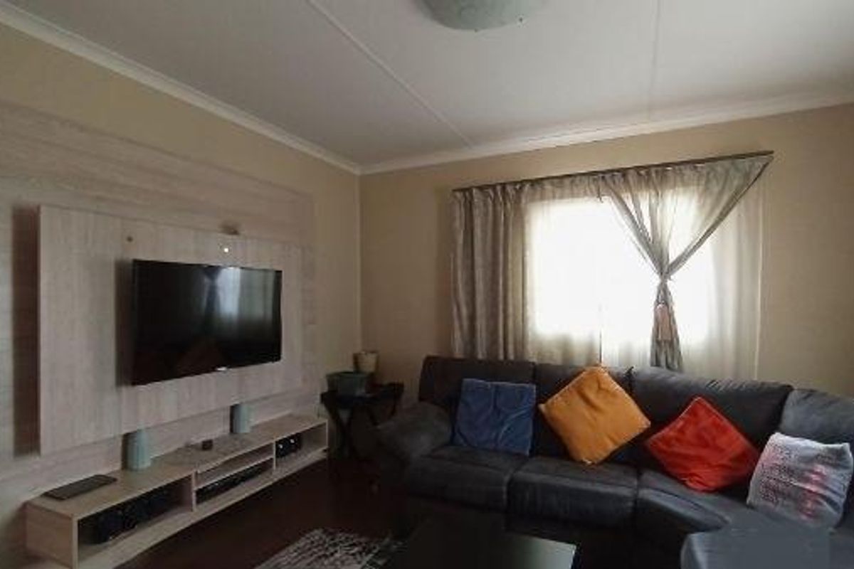 A comfortable living room featuring a built-in wooden media wall unit and neutral wall finishes.