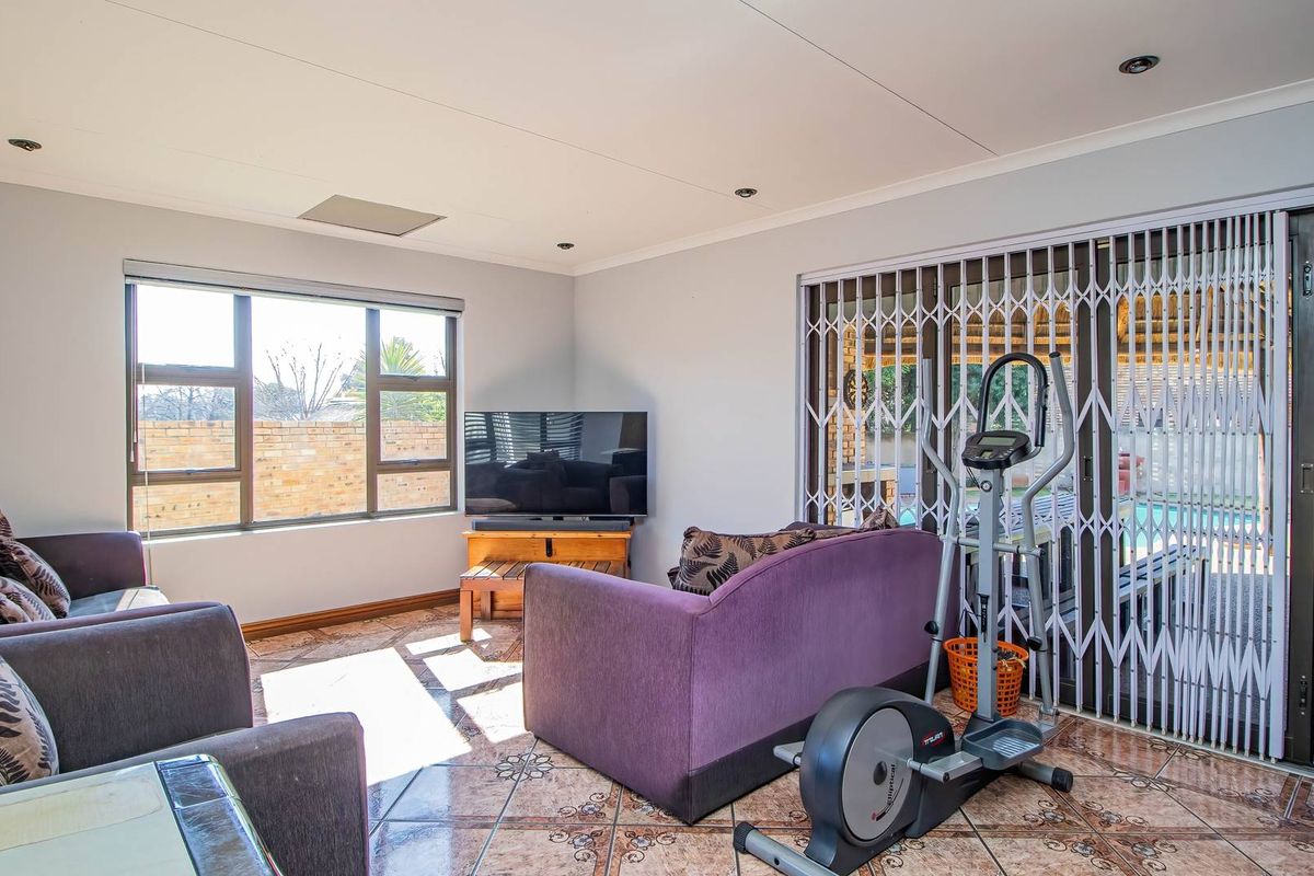 A bright living room featuring tiled flooring, recessed lighting, and sliding glass doors with security gates providing access to the outdoor area.