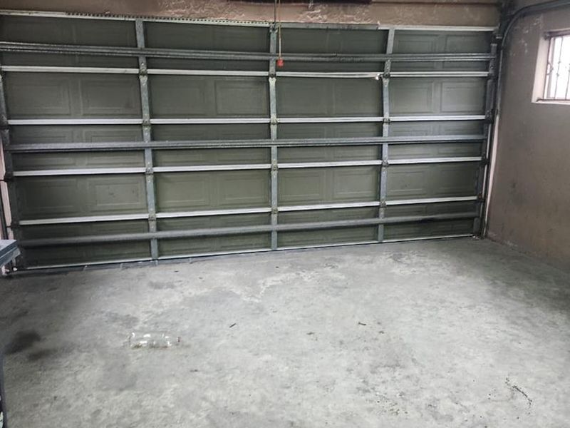 A functional garage space featuring a sectional door, concrete flooring, and exposed wall finishes, suitable for vehicle storage or workshop use.