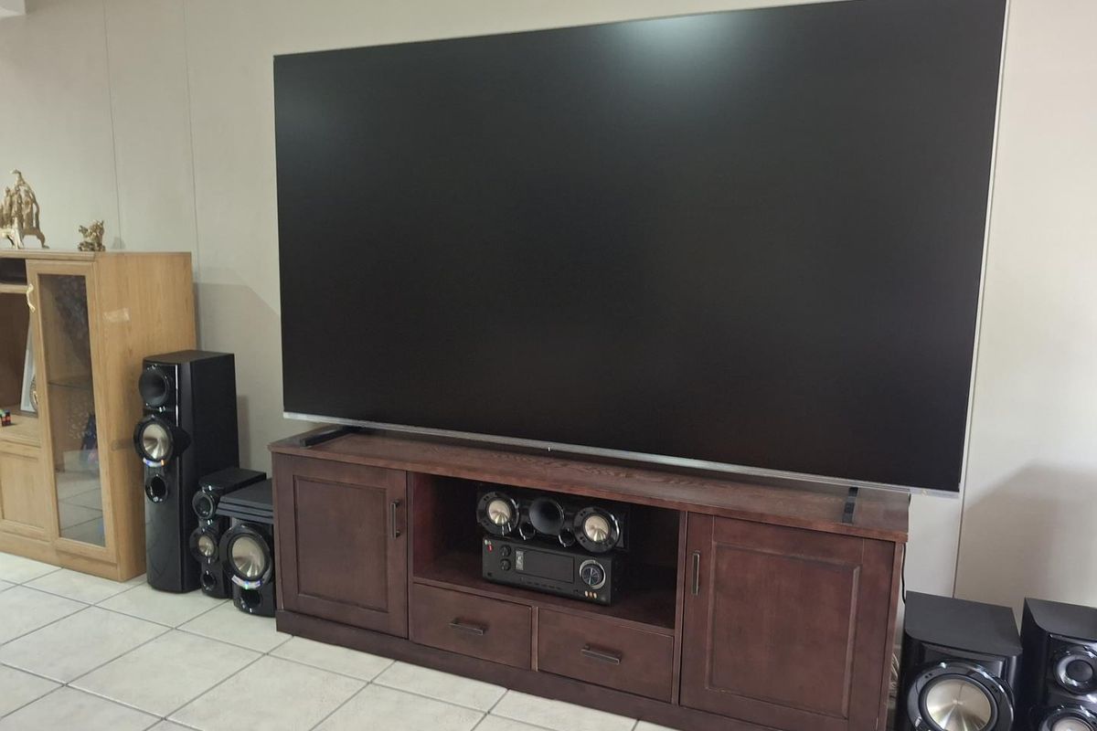 A living room area featuring neutral wall tones and tiled flooring, currently set up as a home entertainment space.