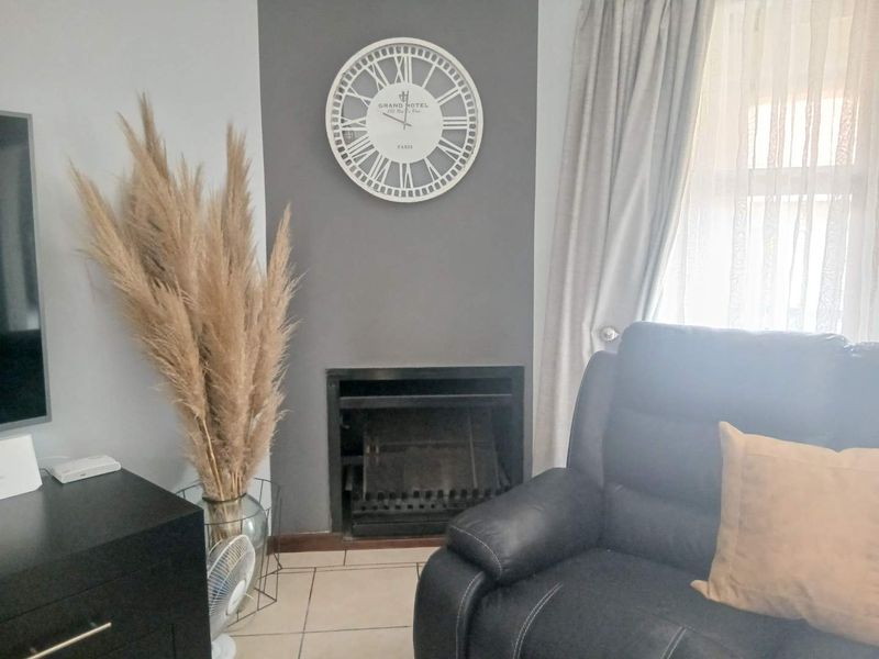 A cozy living room featuring a built-in fireplace with a grey accent wall and neutral tiled flooring.