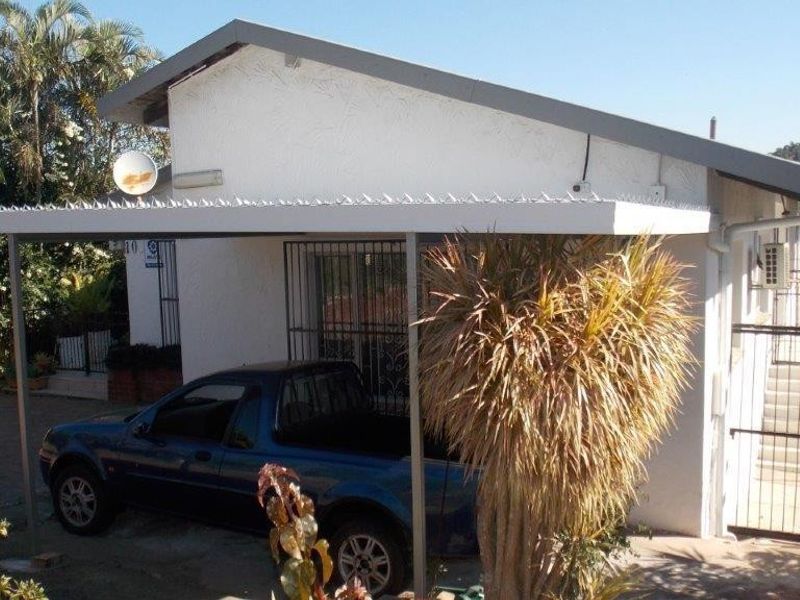 Front exterior view of the property featuring a covered carport, security gates, and security bars on windows.