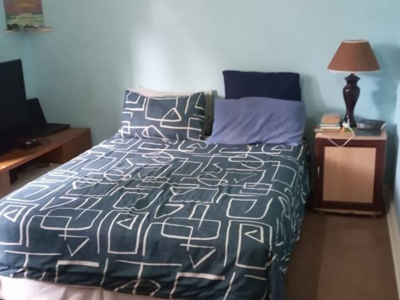 A standard bedroom featuring light blue walls and carpeted flooring, providing a functional space for rest.