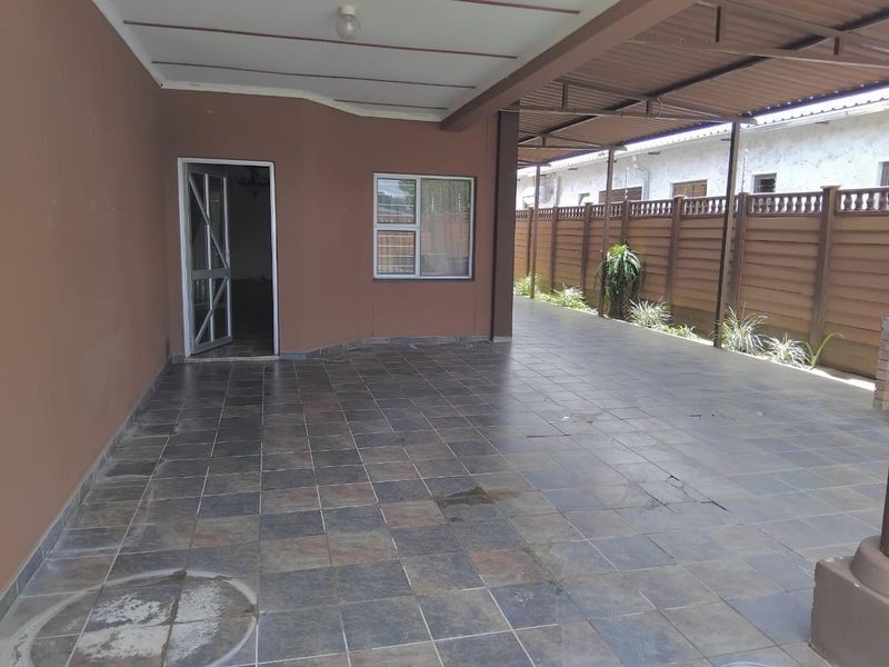 A spacious covered patio area featuring tiled flooring and perimeter fencing, providing a functional outdoor space for relaxation or entertainment.