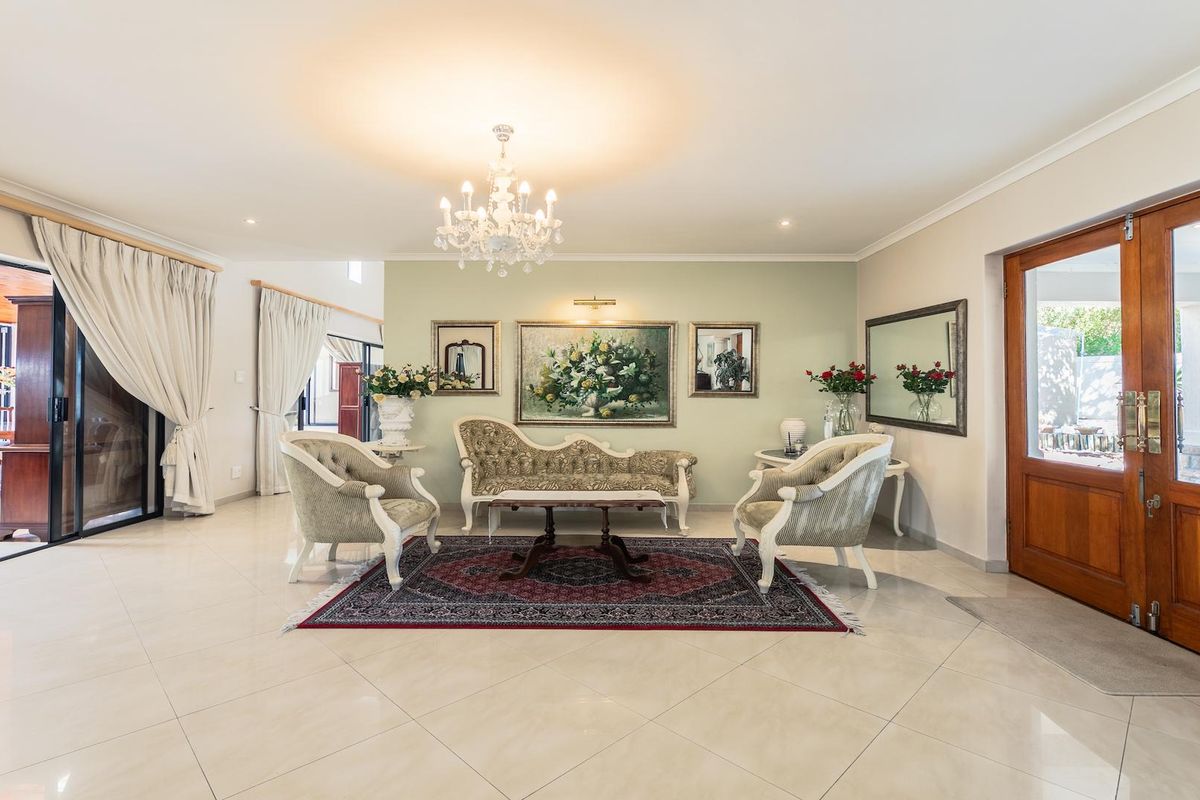 Spacious living area featuring polished tile flooring, a decorative chandelier, and large wooden double doors leading to the exterior.
