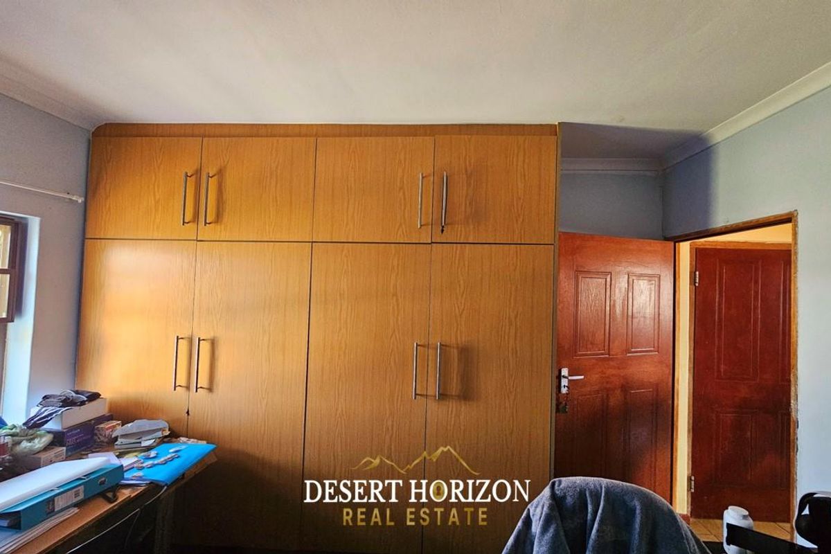 A bedroom featuring built-in wooden cupboards with modern handles and a solid timber door.