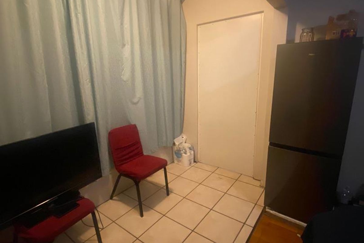 A small interior space featuring tiled flooring, a transition to wood-look flooring, and a doorway, suitable for a compact living or utility area.