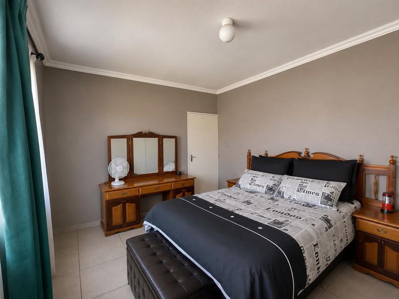 A well-maintained bedroom featuring neutral wall tones, tiled flooring, and classic ceiling cornice detailing.