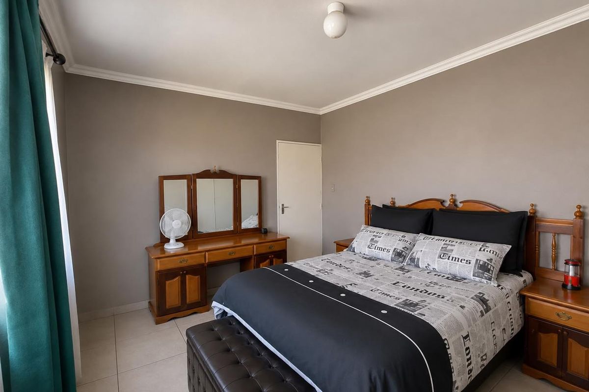 A well-maintained bedroom featuring neutral wall tones, tiled flooring, and classic ceiling cornice detailing.