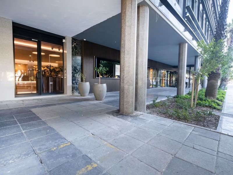 Modern apartment building entrance featuring stone columns, paved walkway, and glass facade with recessed lighting.