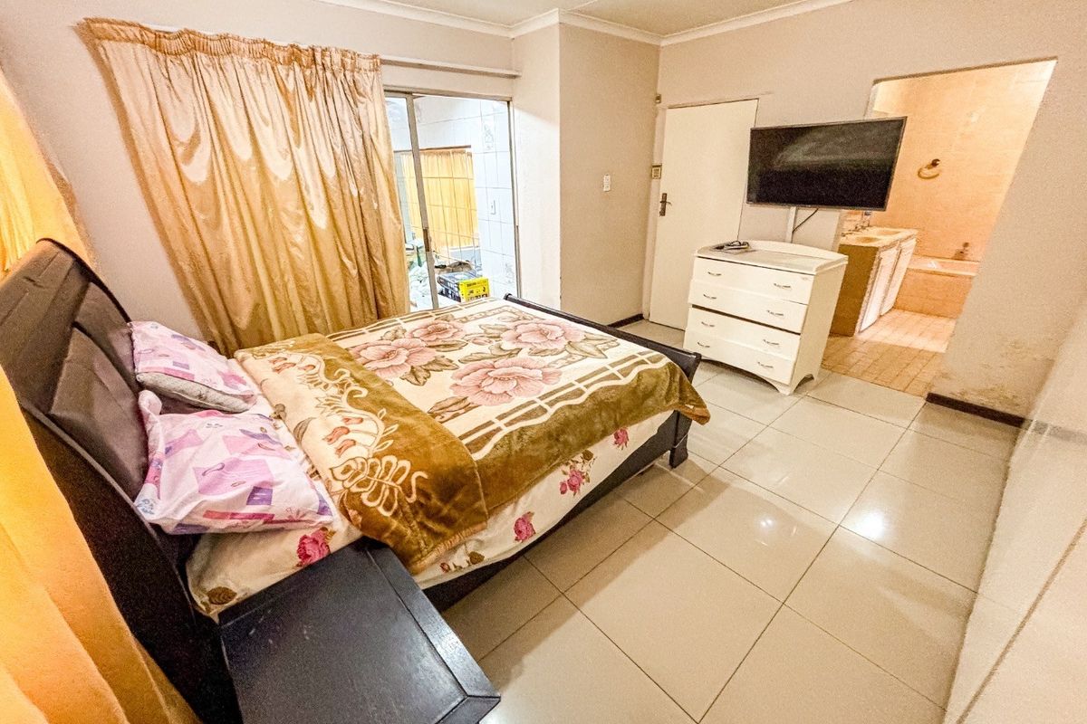 Spacious bedroom featuring tiled flooring, sliding door access to the exterior, and an adjoining en-suite bathroom.