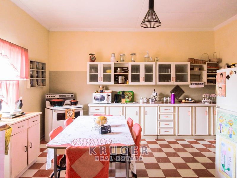 A dated kitchen featuring traditional cabinetry, a freestanding stove, and checkered floor tiles, offering significant potential for a modern renovation.
