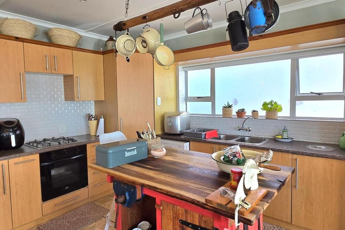 A functional kitchen featuring light wood cabinetry, a subway tile backsplash, integrated oven, gas hob, and a central wooden island workspace.