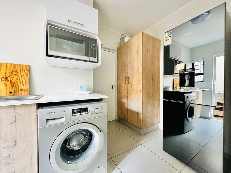 A functional laundry area featuring built-in cabinetry, tiled flooring, and space for appliances, providing efficient utility storage and workspace.