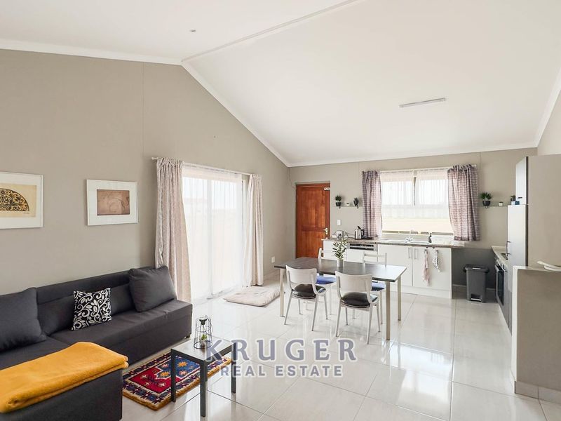 Spacious open-plan living area featuring a vaulted ceiling, tiled floors, and a functional kitchen with built-in cabinetry and appliances.