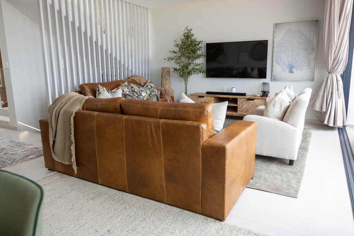 Modern living room featuring tiled flooring, a decorative vertical slat room divider, and large sliding glass doors providing access to the outdoor area.