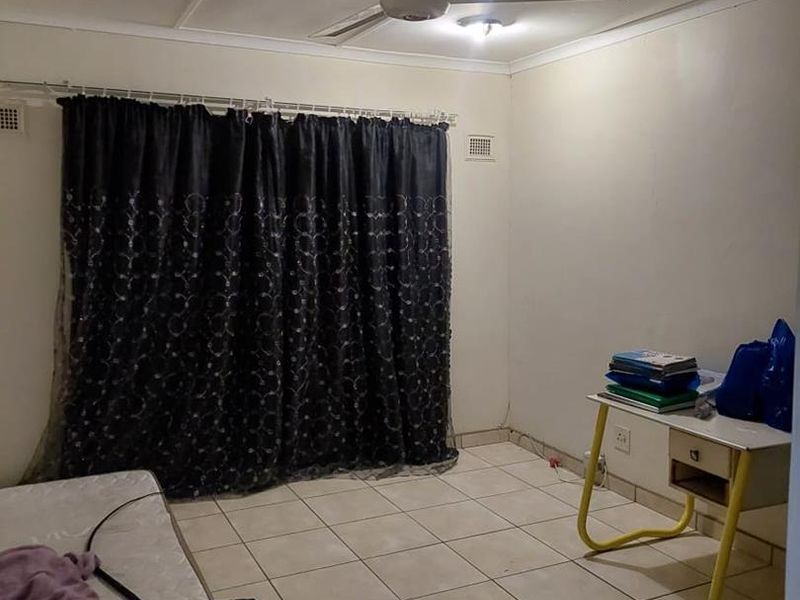 A bedroom featuring tiled flooring and a ceiling fan, requiring cosmetic updates to improve the overall finish and appeal.