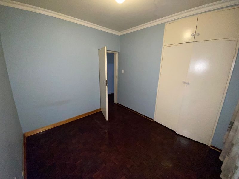 An empty bedroom featuring parquet flooring, built-in cupboards, and blue painted walls with crown molding.