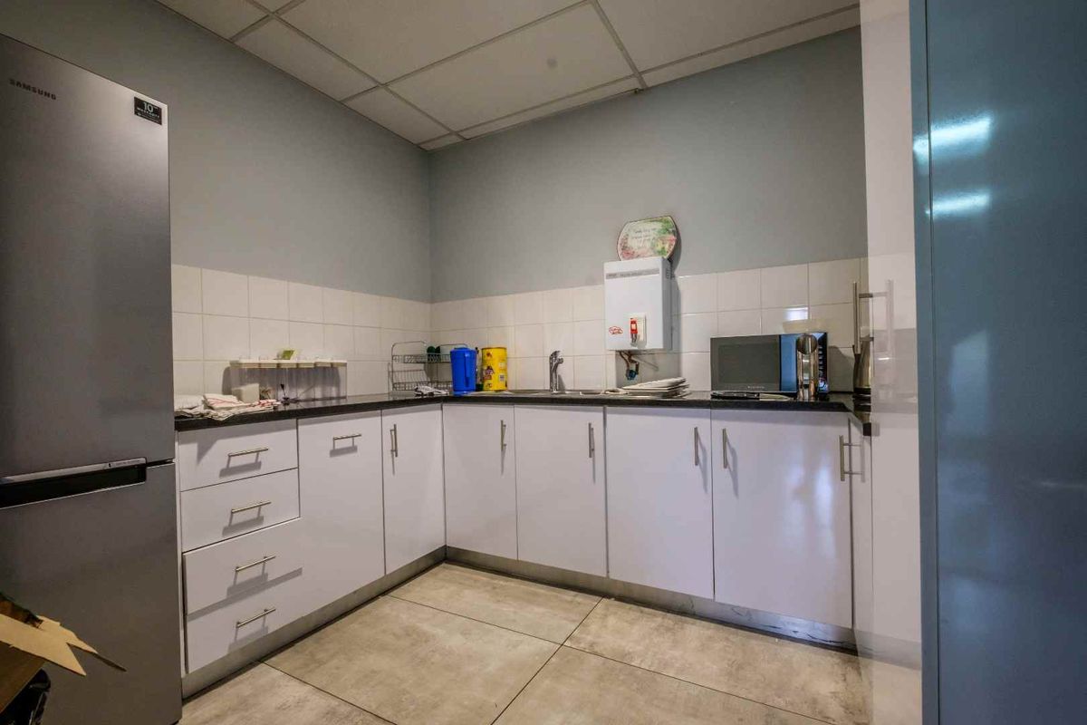 A functional kitchen area featuring white built-in cabinetry, dark laminate countertops, a tiled backsplash, and tiled flooring.