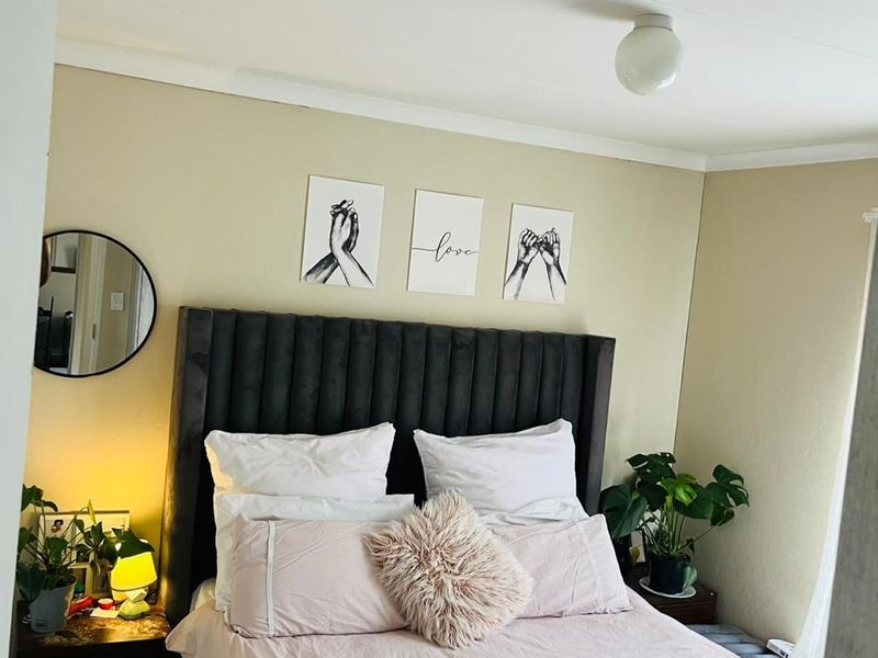 A cozy bedroom featuring neutral wall tones and a central ceiling light fixture.