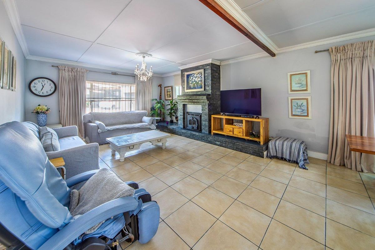 Spacious living room featuring tiled flooring, a prominent stone-clad fireplace, and an exposed ceiling beam, offering a comfortable and functional family space.