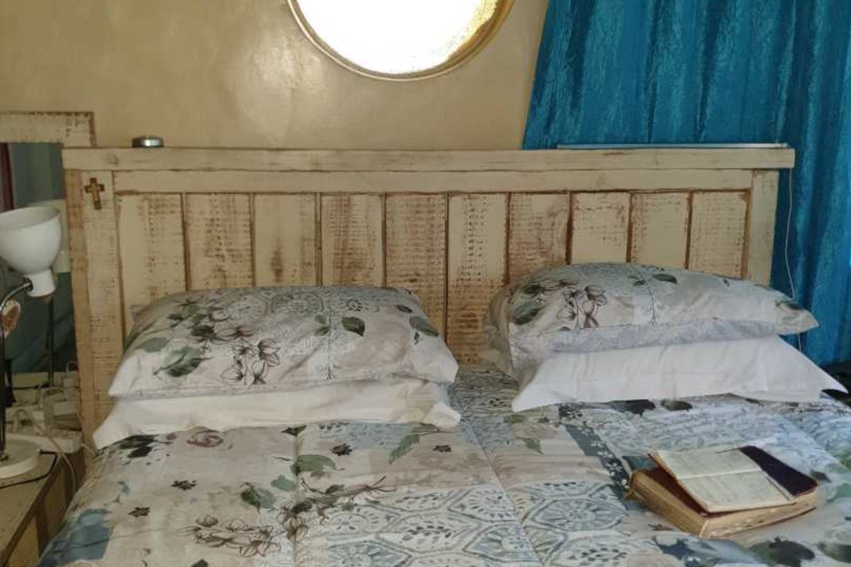 A bedroom featuring a distinctive circular window and a rustic, distressed-finish wooden headboard.