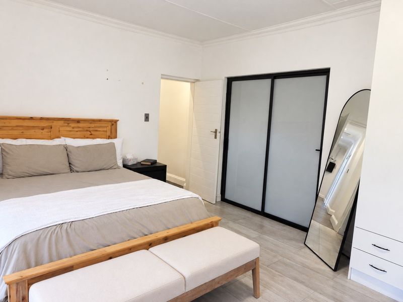 A well-maintained bedroom featuring tiled flooring, coved ceilings, and a modern built-in wardrobe with sliding frosted glass doors.