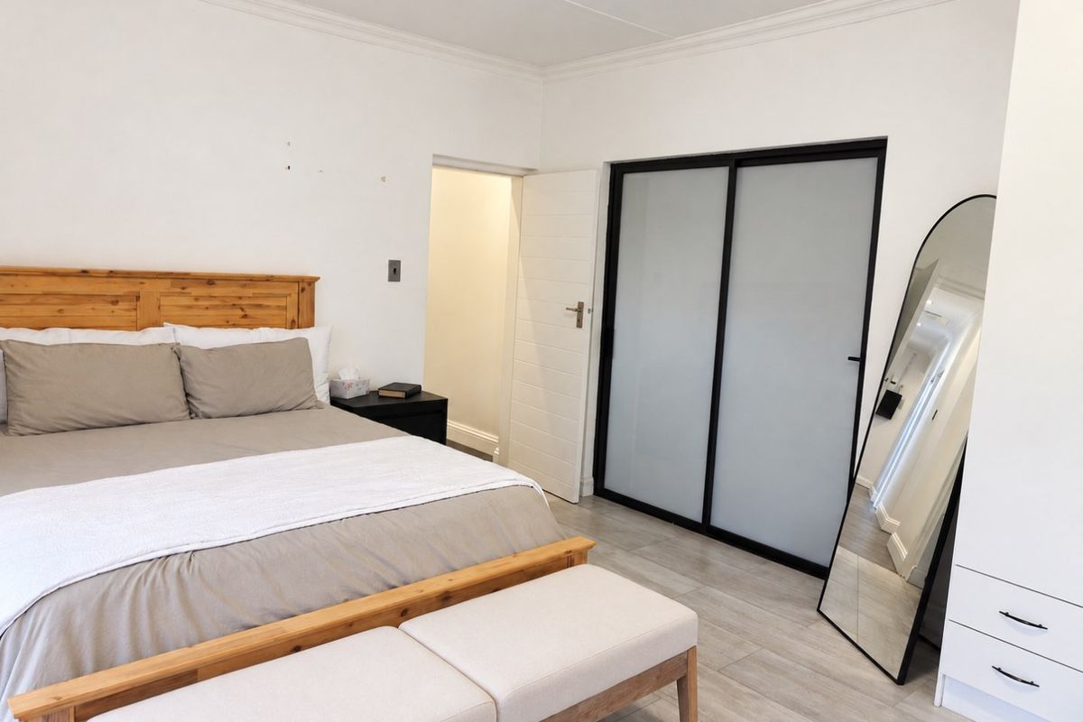A well-maintained bedroom featuring tiled flooring, coved ceilings, and a modern built-in wardrobe with sliding frosted glass doors.