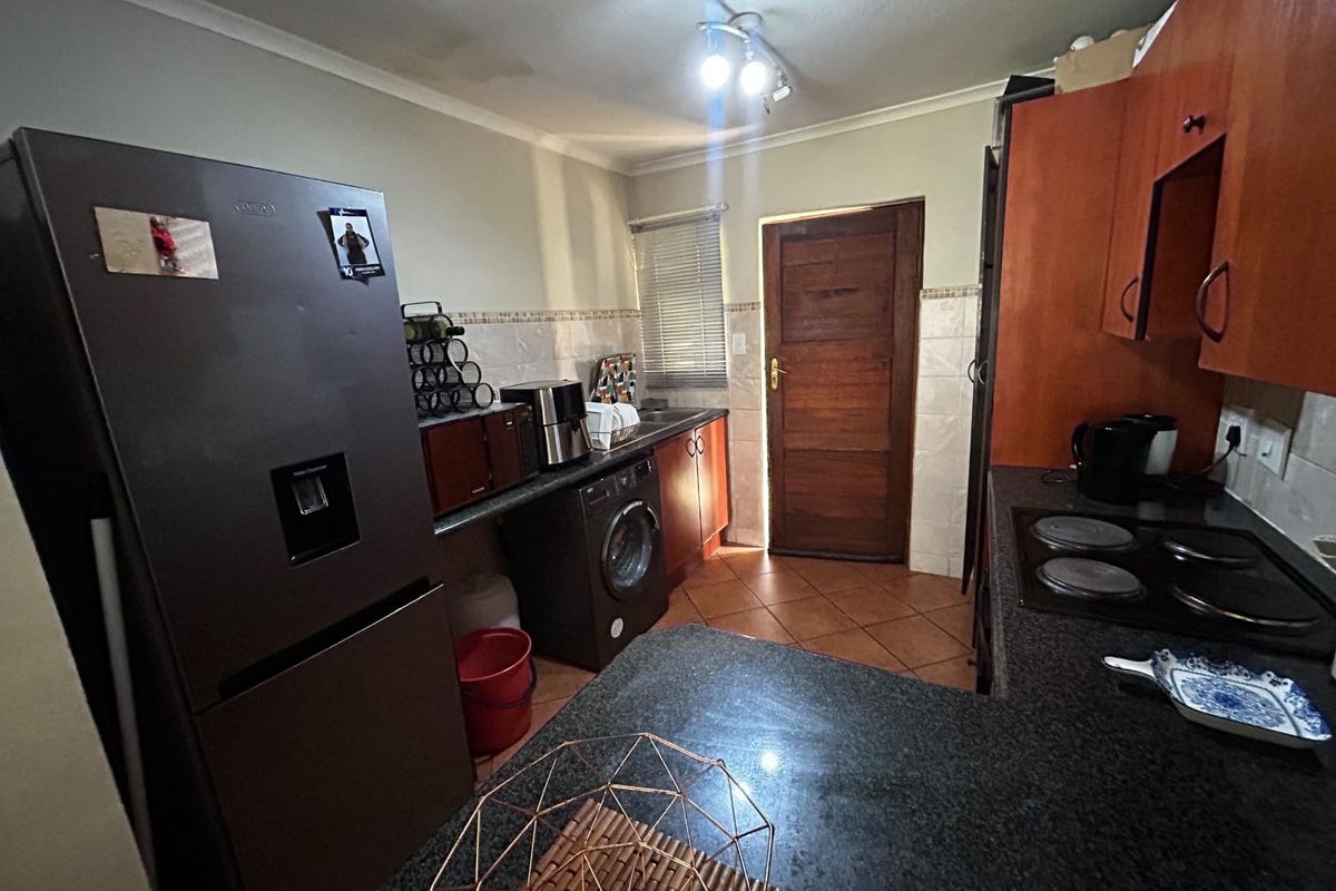 Functional kitchen featuring granite countertops, built-in cabinetry, electric hob, and direct access to an exterior door.
