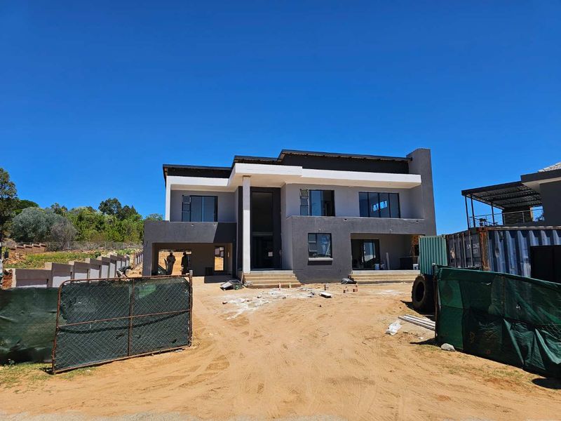 A modern double-story residential property under construction, featuring a contemporary facade, flat roof design, and large aluminum-framed windows.