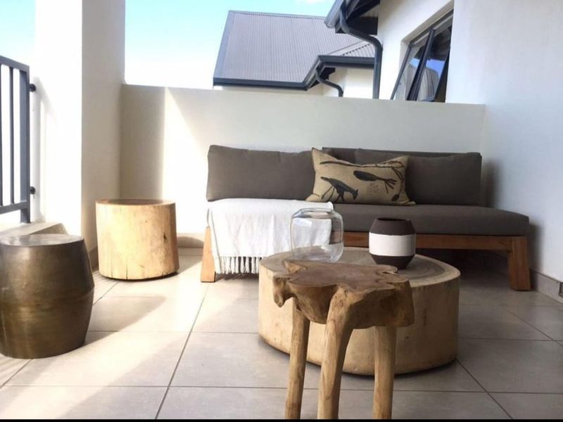 A covered balcony featuring tiled flooring and a metal balustrade, providing a pleasant outdoor space for relaxation.
