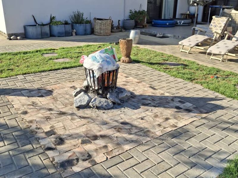 Outdoor paved patio area featuring a central fire pit, direct access to the home via sliding doors, and an exterior wall-mounted air conditioning unit.