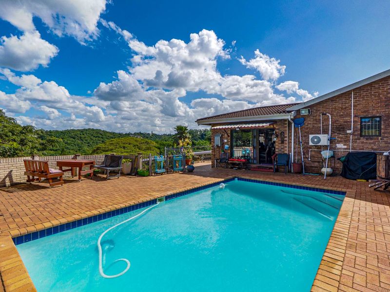 Outdoor pool area featuring brick paving, a swimming pool, and direct access to the home via sliding glass doors with scenic landscape views.