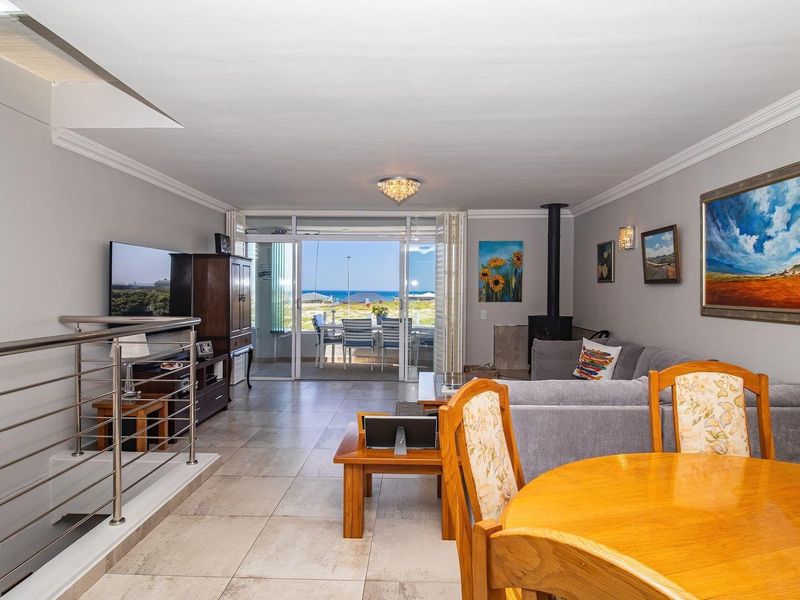 Spacious open-plan living area featuring tiled floors, a fireplace, and large sliding doors opening to a patio with ocean views.