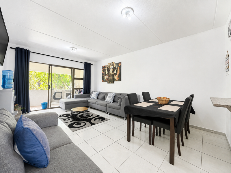 Open plan living and dining area featuring tiled flooring and large sliding glass doors leading to a balcony.