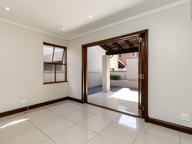 Bright and spacious living area featuring neutral tiled floors, recessed lighting, and large folding doors that open onto a private patio.