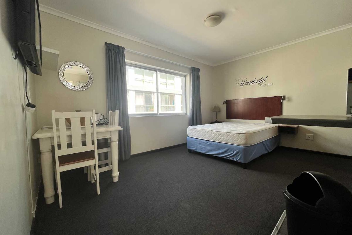A functional bedroom featuring a built-in headboard, integrated desk space, and carpeted flooring, offering a practical layout for comfortable living.